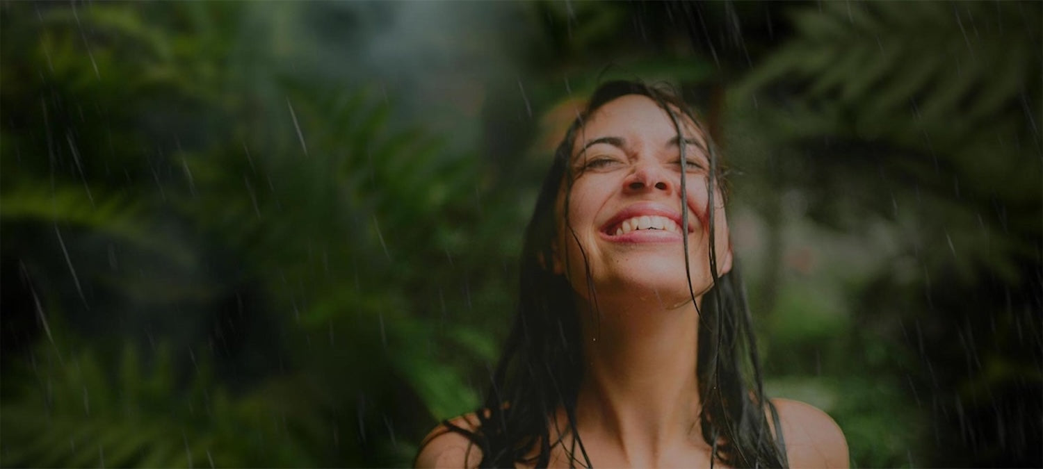 Smiling woman with raindrops on her face symbolizing rejuvenation – Rejuv Wellness hero banner